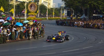 Red Bull’s Mark Webber drives past Thai fans